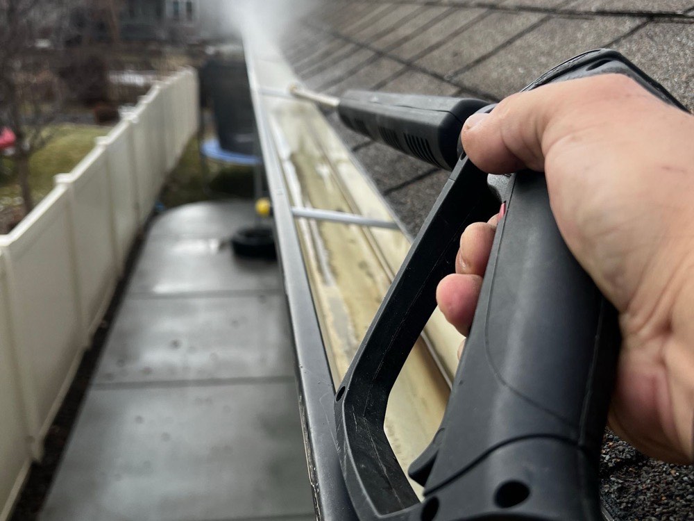 A gutter being cleared with a cleaning tool